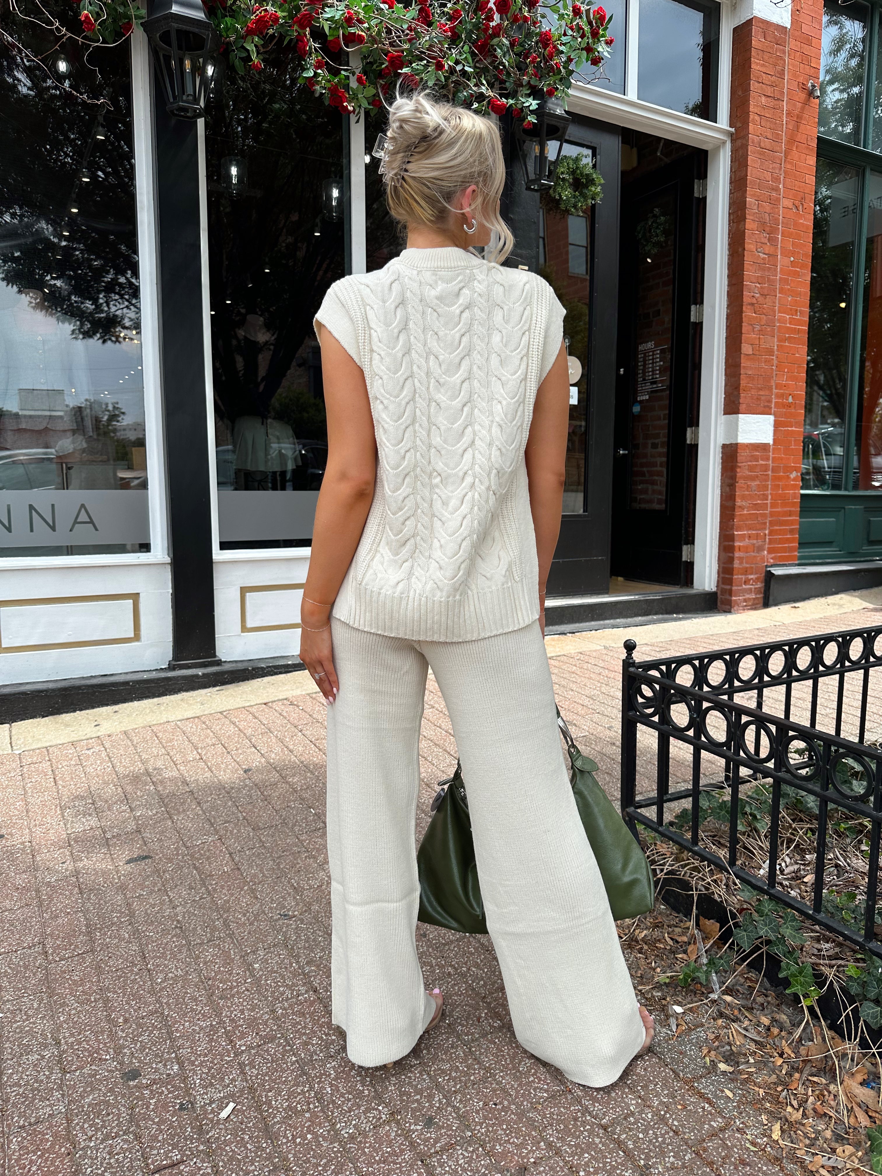 Woman wearing cream two piece sweater set with open side detailing. 