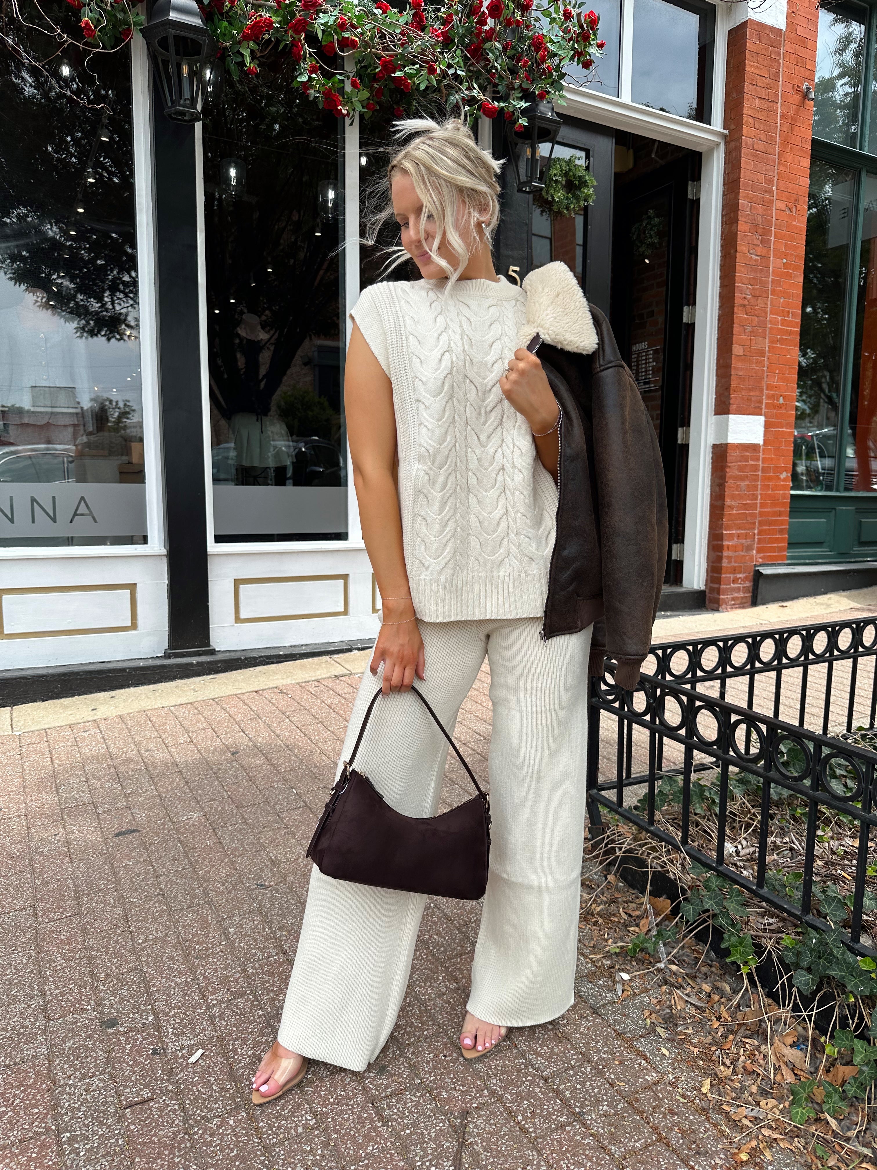 Woman wearing cream two piece sweater set with open side detailing. 