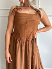 Woman wearing brown suede corset style midi dress with flowy skirt. 