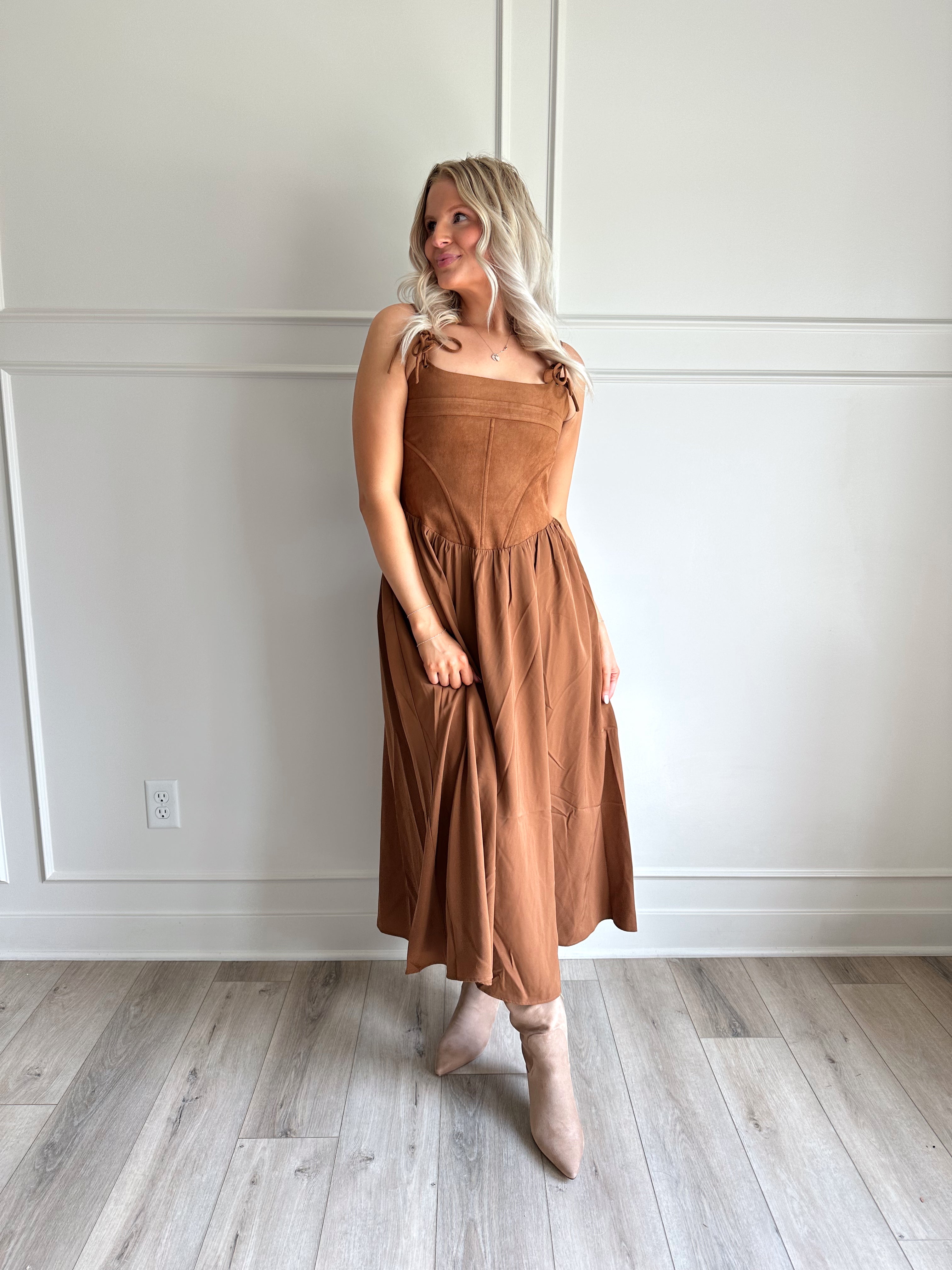 Woman wearing brown suede corset style midi dress with flowy skirt. 