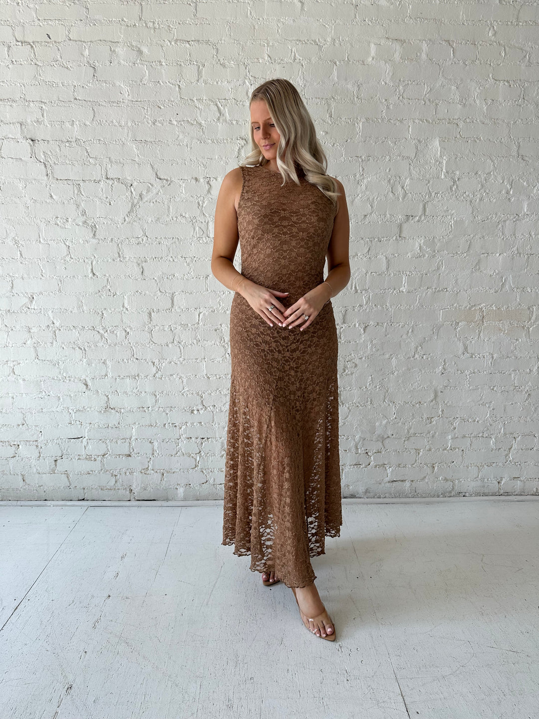 Woman wearing brown lace maxi dress with clear heels.