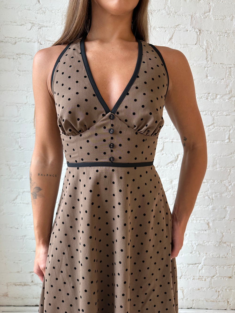 Woman wearing brown and black polka dot halter midi dress with a fit to flare style.