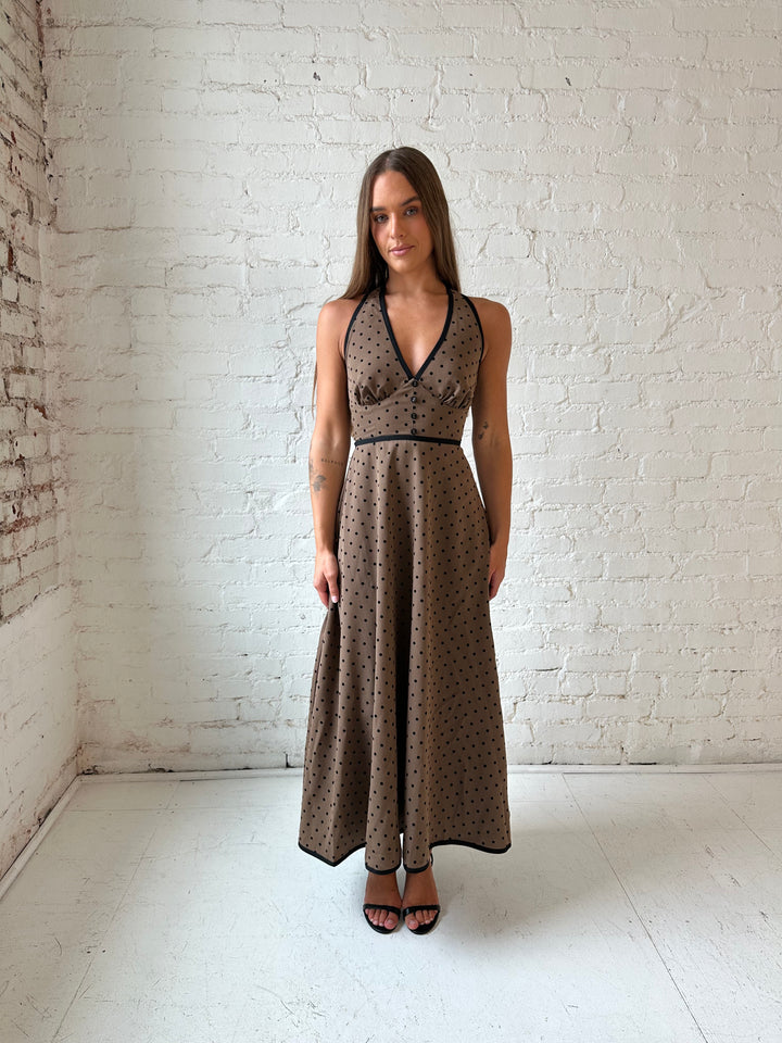 Woman wearing brown and black polka dot halter midi dress with a fit to flare style.