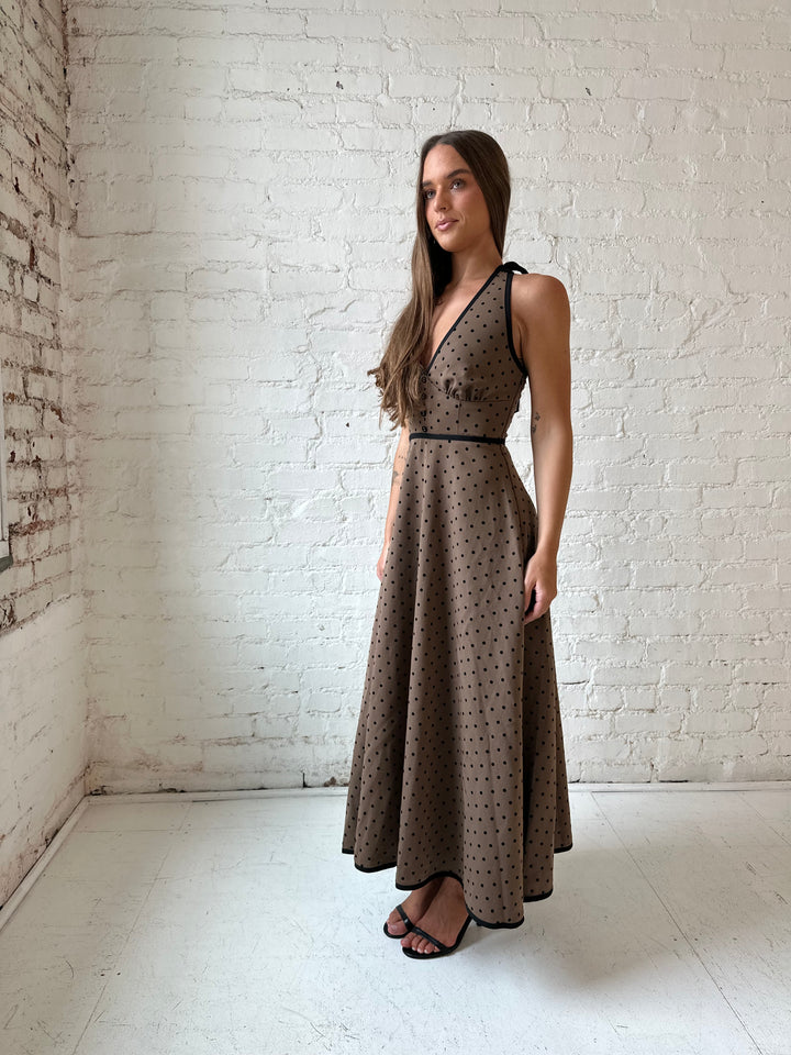 Woman wearing brown and black polka dot halter midi dress with a fit to flare style.