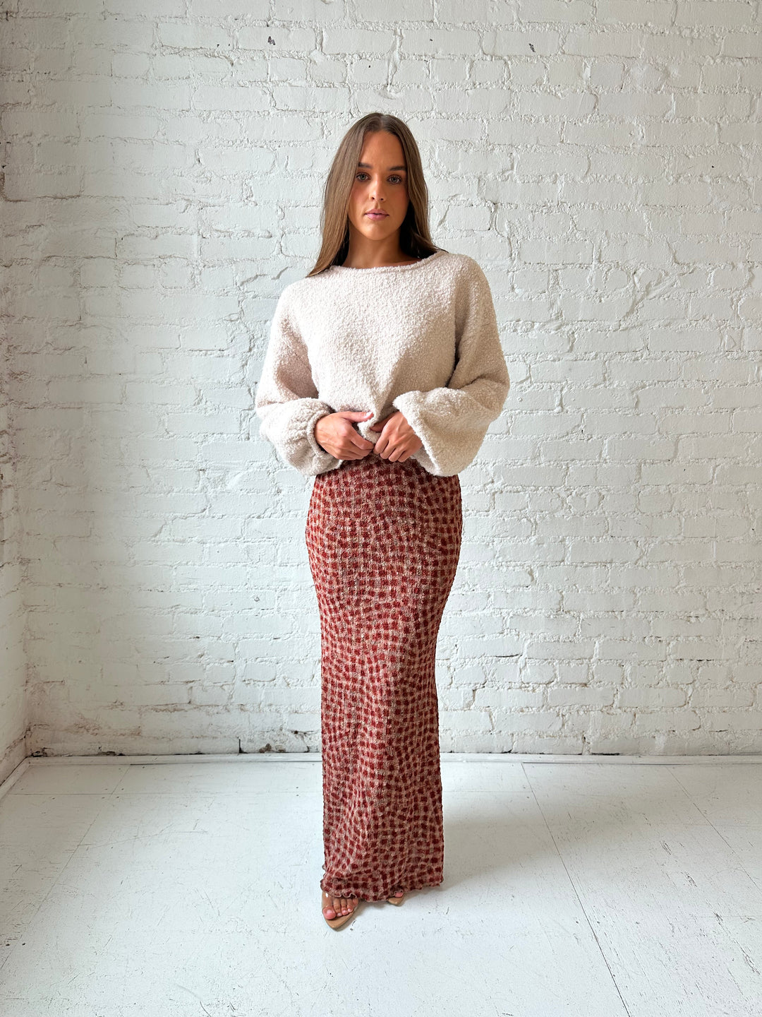 Woman wearing beige knit sweater with burgundy dotted maxi skirt.