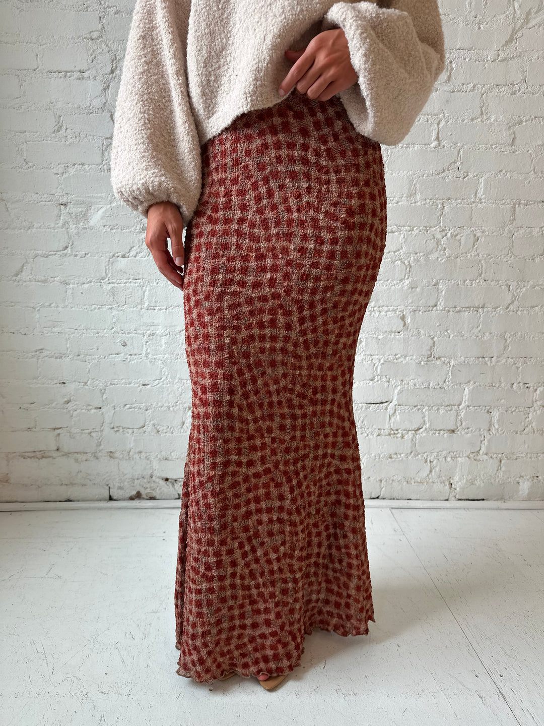 Woman wearing beige knit sweater with burgundy dotted maxi skirt.