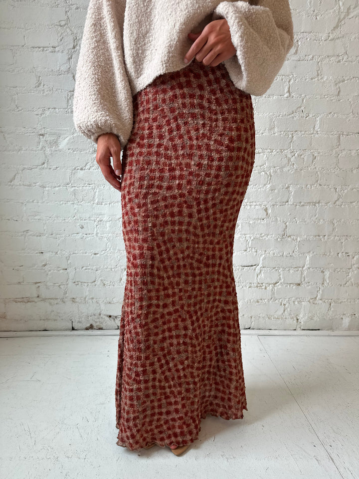 Woman wearing beige knit sweater with burgundy dotted maxi skirt.