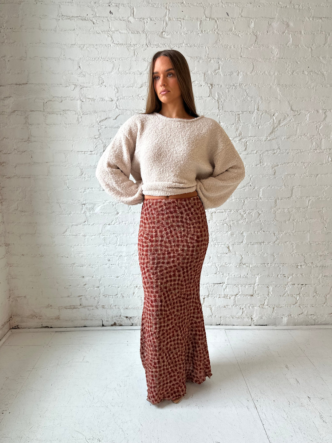 Woman wearing beige knit sweater with burgundy dotted maxi skirt.