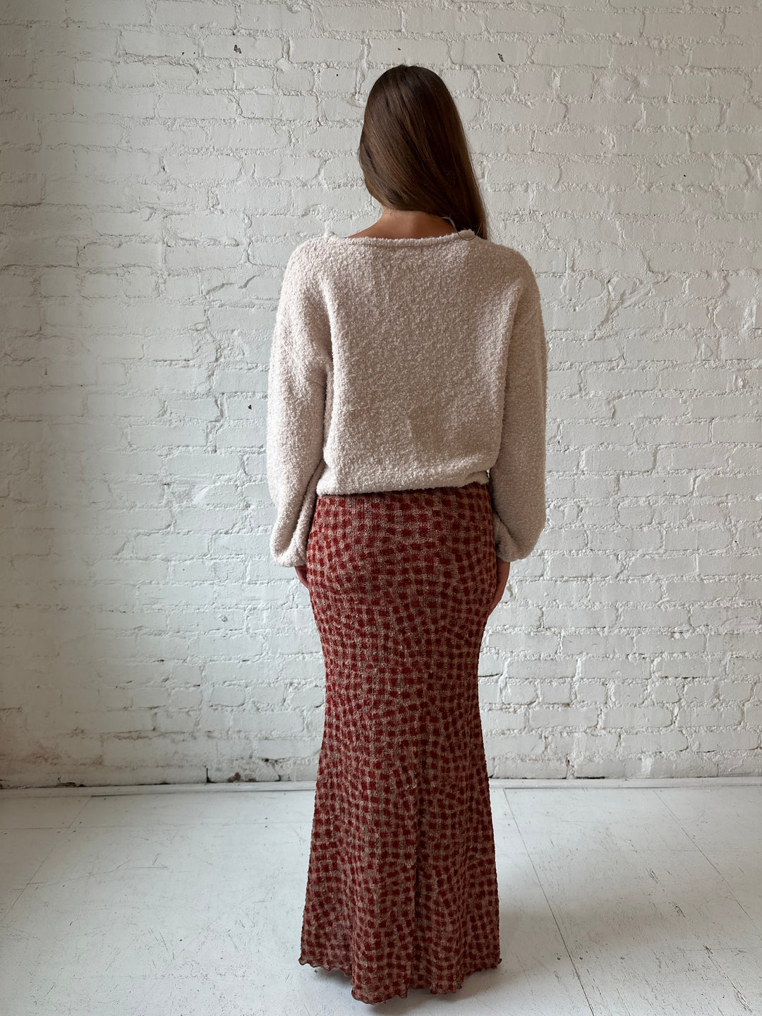 Woman wearing beige knit sweater with burgundy dotted maxi skirt.