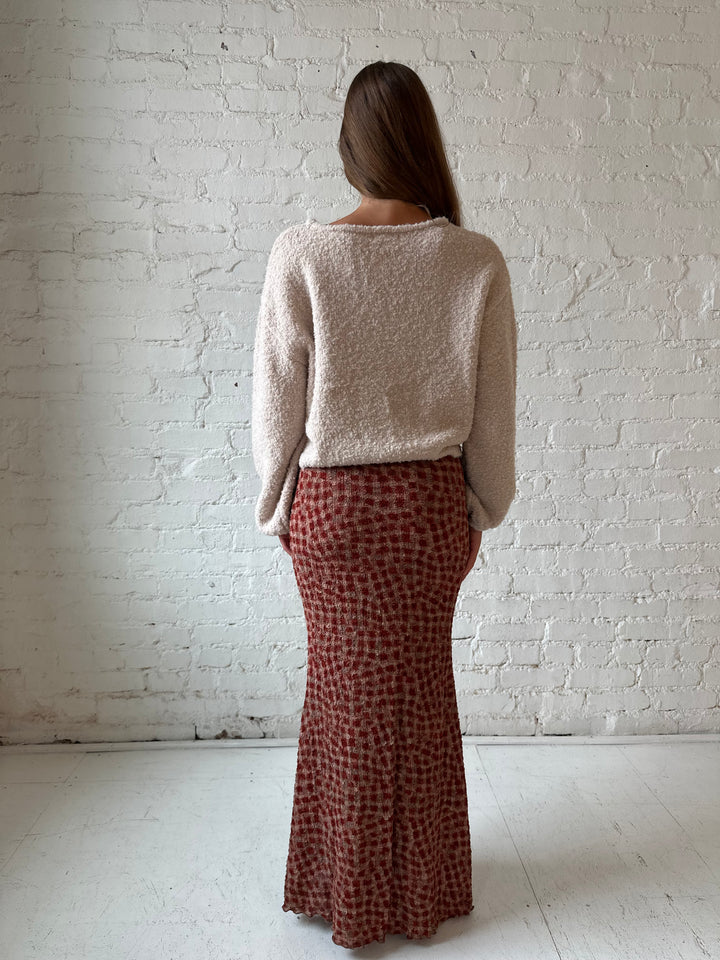 Woman wearing beige knit sweater with burgundy dotted maxi skirt.