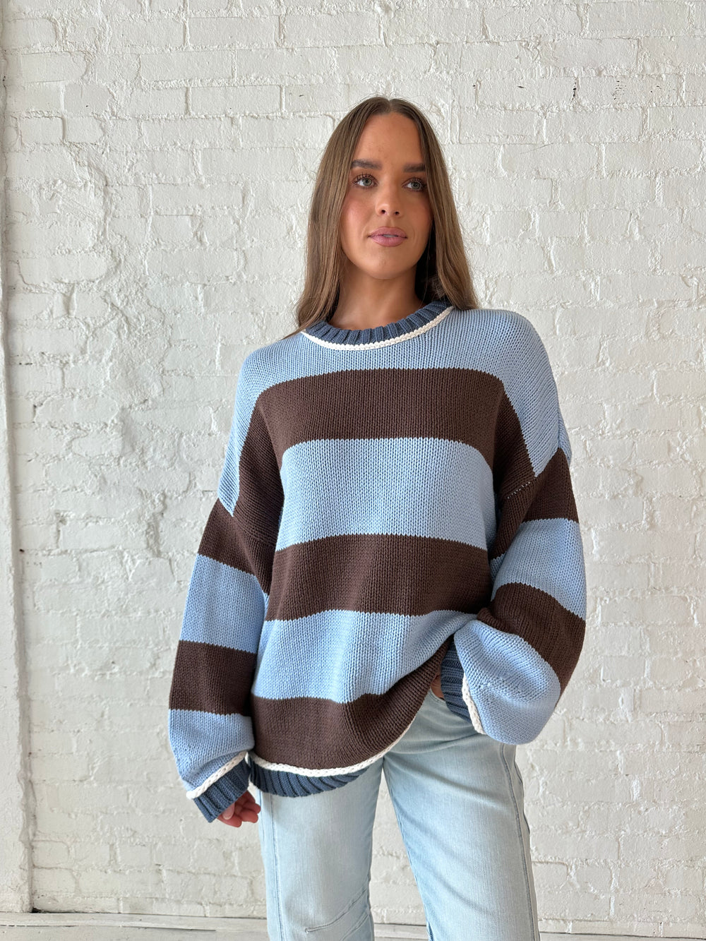 Woman wearing blue and brown oversized chinky sweater with a light wash barrel jean. 