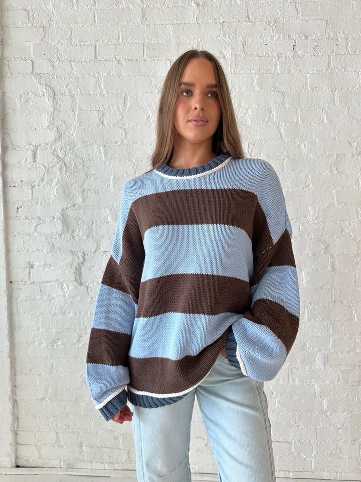 Woman wearing blue and brown oversized chinky sweater with a light wash barrel jean. 