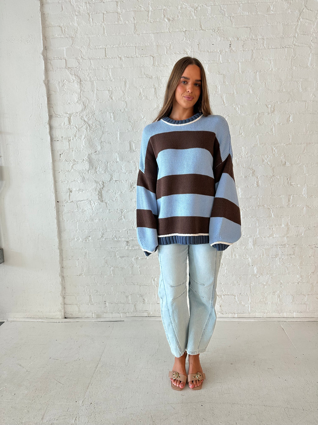 Woman wearing blue and brown oversized chinky sweater with a light wash barrel jean. 