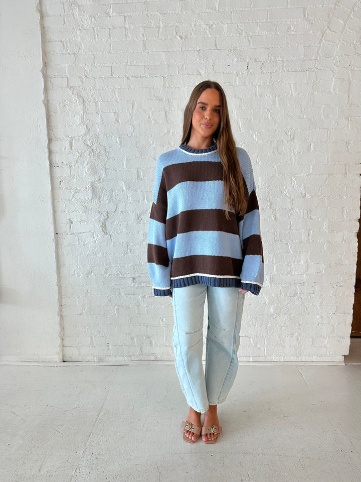 Woman wearing blue and brown oversized chinky sweater with a light wash barrel jean. 