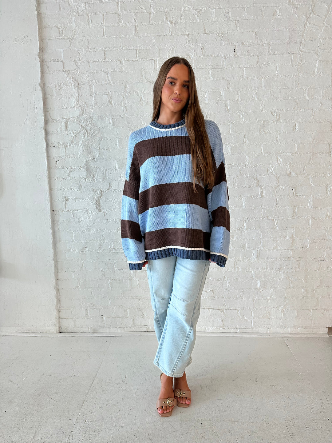 Woman wearing blue and brown oversized chinky sweater with a light wash barrel jean. 