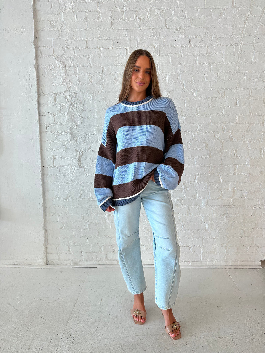 Woman wearing blue and brown oversized chinky sweater with a light wash barrel jean. 