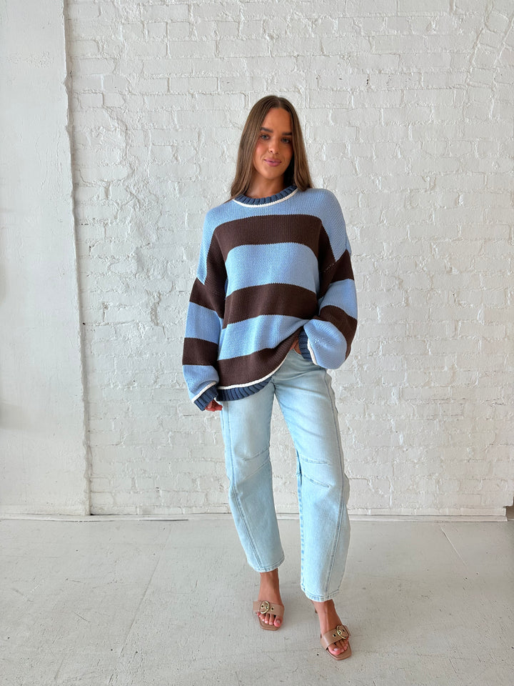 Woman wearing blue and brown oversized chinky sweater with a light wash barrel jean. 