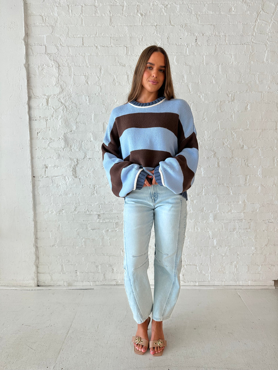 Woman wearing blue and brown oversized chinky sweater with a light wash barrel jean. 