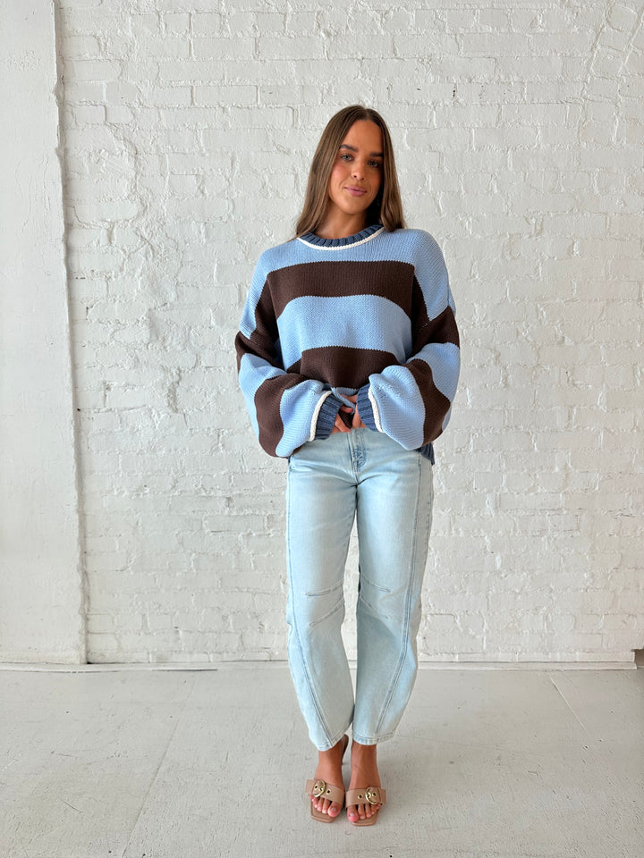 Woman wearing blue and brown oversized chinky sweater with a light wash barrel jean. 