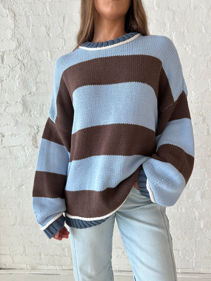 Woman wearing blue and brown oversized chinky sweater with a light wash barrel jean. 