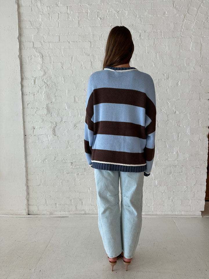 Woman wearing blue and brown oversized chinky sweater with a light wash barrel jean. 
