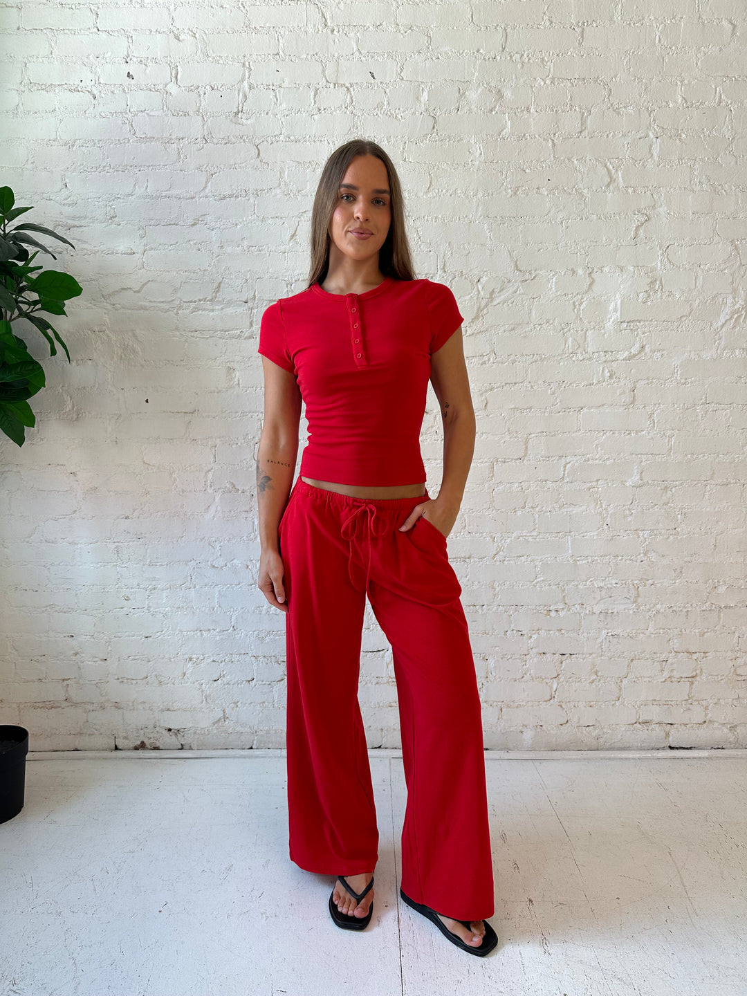 Woman wearing bright red two piece wide leg lounge set with short sleeve fitted top. 