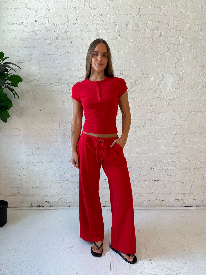 Woman wearing bright red two piece wide leg lounge set with short sleeve fitted top. 