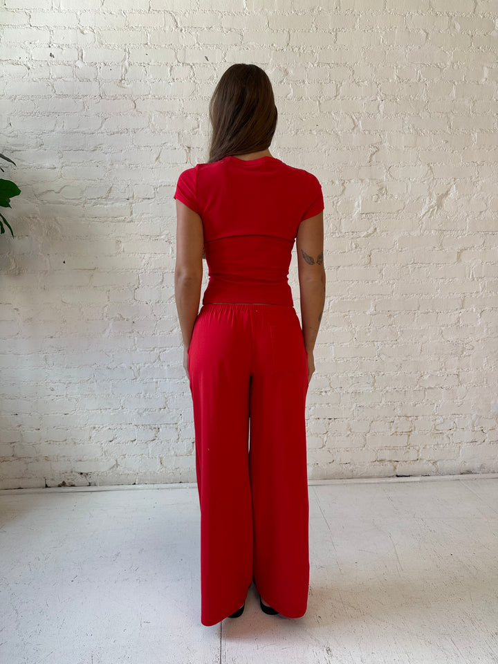 Woman wearing bright red two piece wide leg lounge set with short sleeve fitted top. 