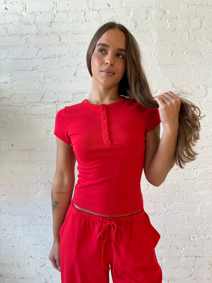 Woman wearing bright red two piece wide leg lounge set with short sleeve fitted top. 