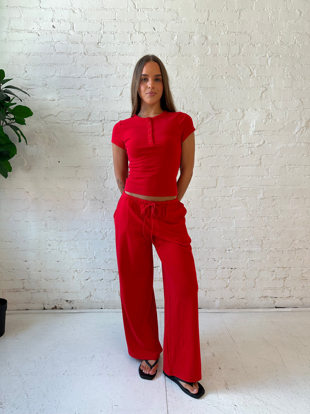 Woman wearing bright red two piece wide leg lounge set with short sleeve fitted top. 
