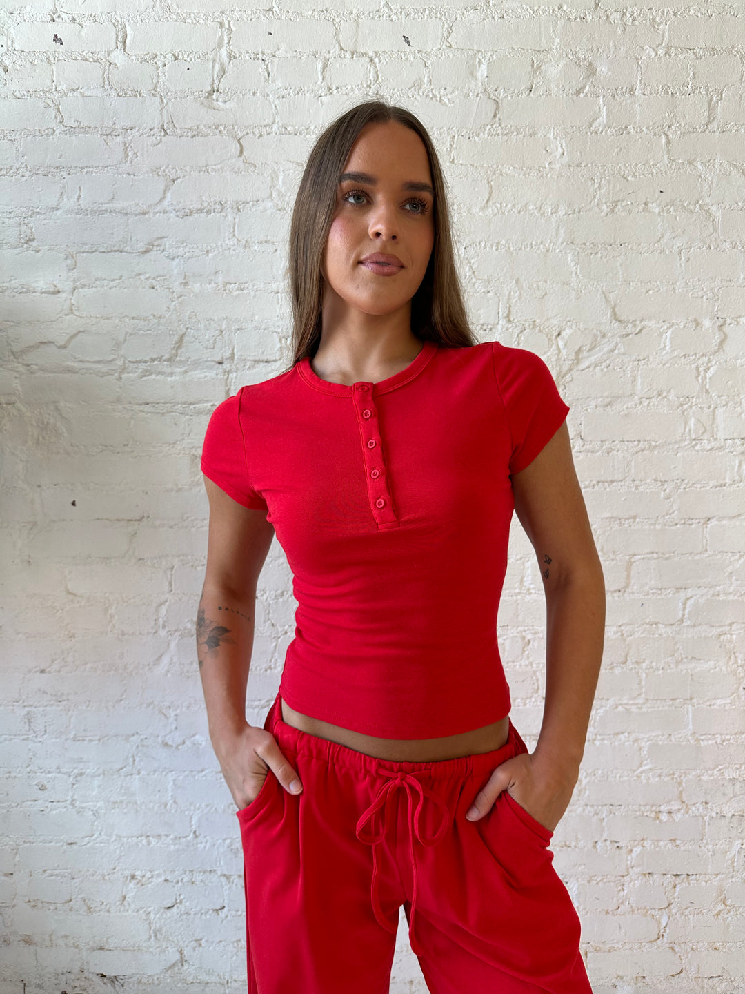 Woman wearing bright red two piece wide leg lounge set with short sleeve fitted top. 