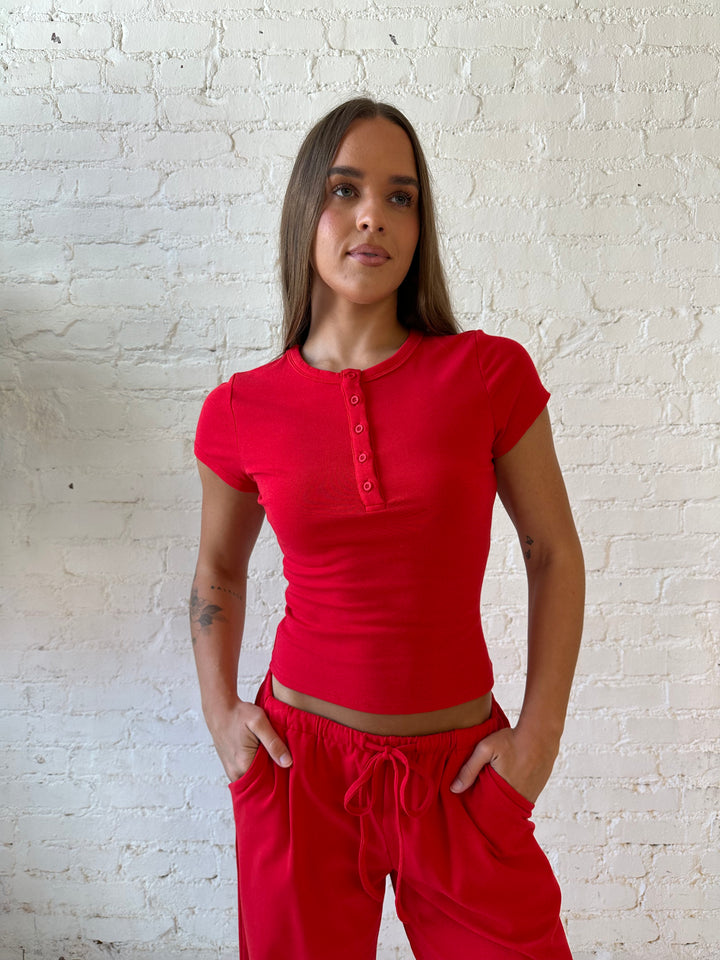 Woman wearing bright red two piece wide leg lounge set with short sleeve fitted top. 