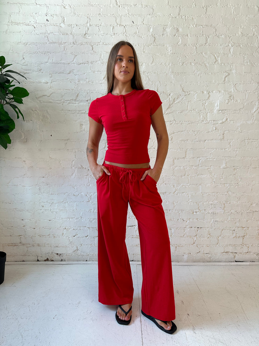 Woman wearing bright red two piece wide leg lounge set with short sleeve fitted top. 