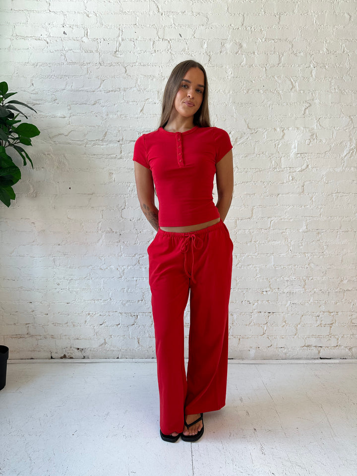 Woman wearing bright red two piece wide leg lounge set with short sleeve fitted top. 