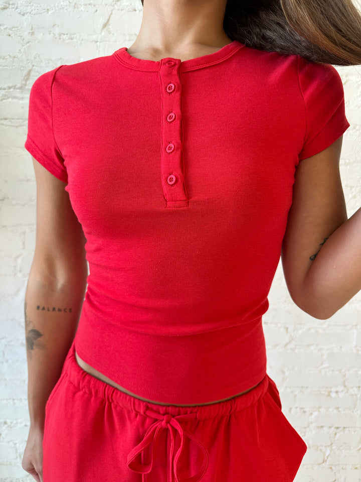 Woman wearing bright red two piece wide leg lounge set with short sleeve fitted top. 