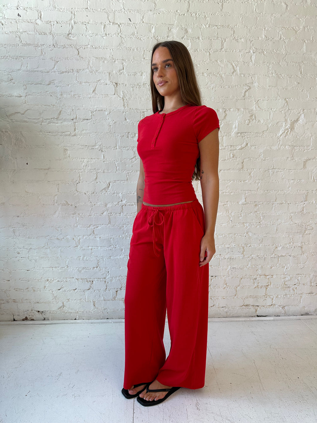 Woman wearing bright red two piece wide leg lounge set with short sleeve fitted top. 