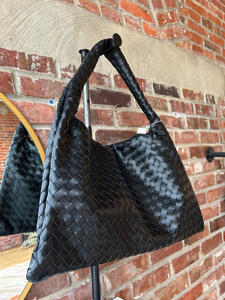 Black woven shoulder bag with magnetic closure. 