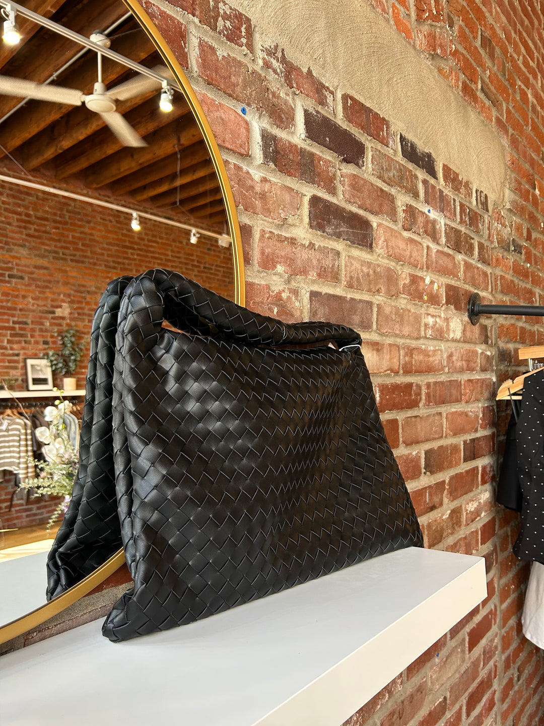Black woven shoulder bag with magnetic closure. 