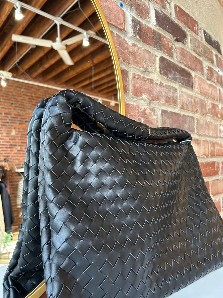 Black woven shoulder bag with magnetic closure. 