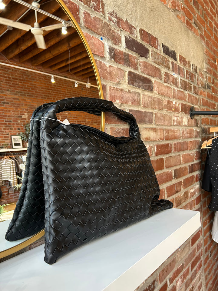 Black woven shoulder bag with magnetic closure. 