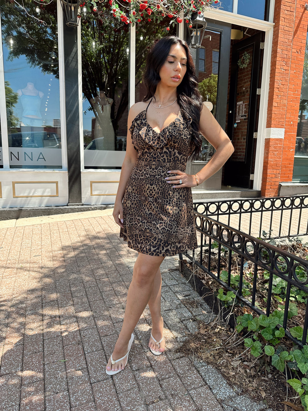 Woman wearing cheetah print mini dress with adjustable straps and ruffle neckline. 