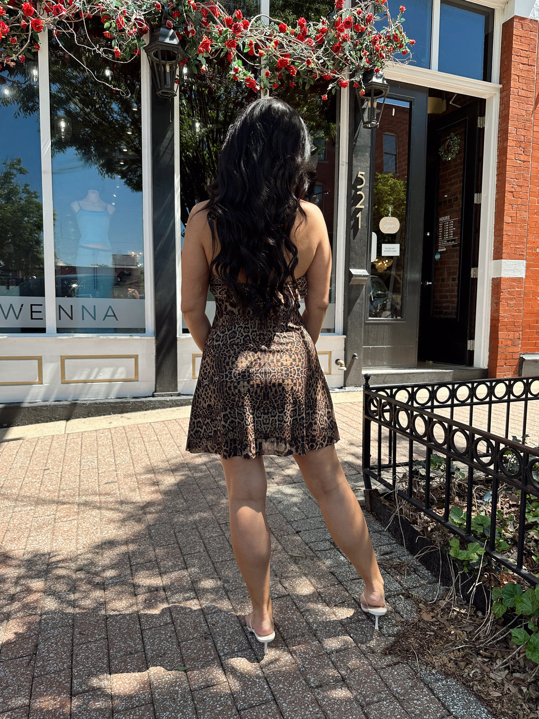 Woman wearing cheetah print mini dress with adjustable straps and ruffle neckline. 