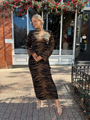 Woman wearing brown zebra print long sleeve sweater dress. 