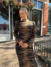 Woman wearing brown zebra print long sleeve sweater dress. 