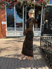 Woman wearing brown zebra print long sleeve sweater dress. 