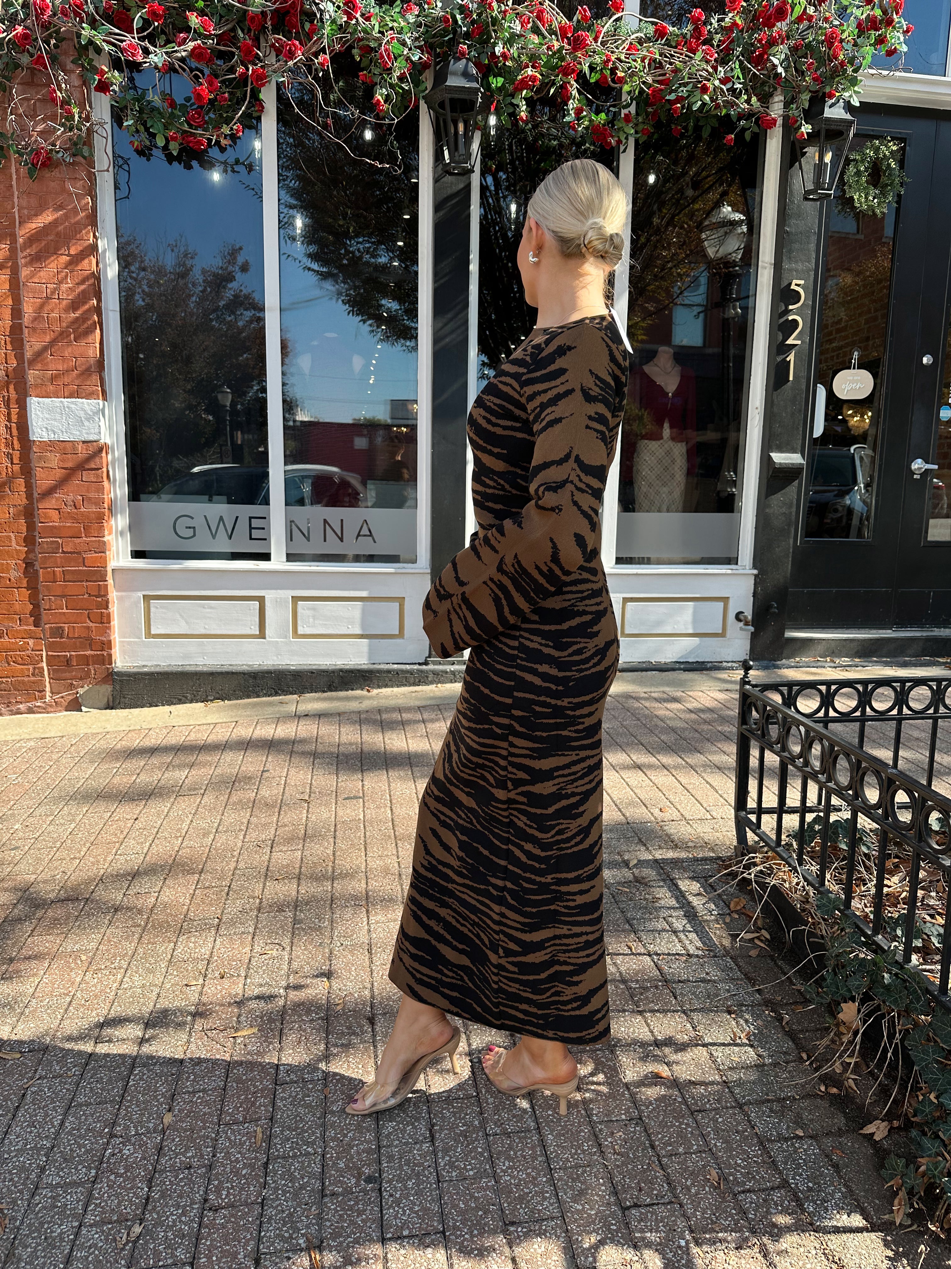 Woman wearing brown zebra print long sleeve sweater dress. 
