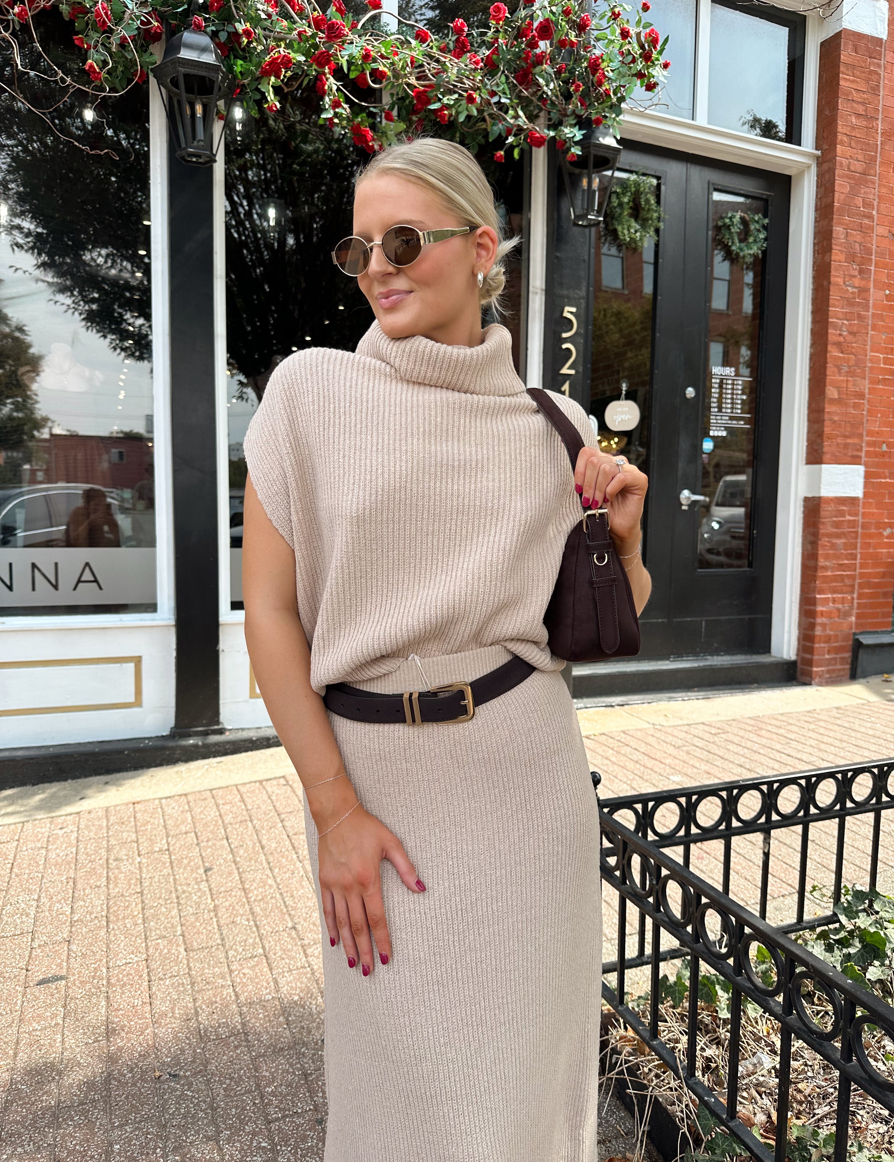 Woman wearing a beige knit two piece sweater set with midi skirt and belt.