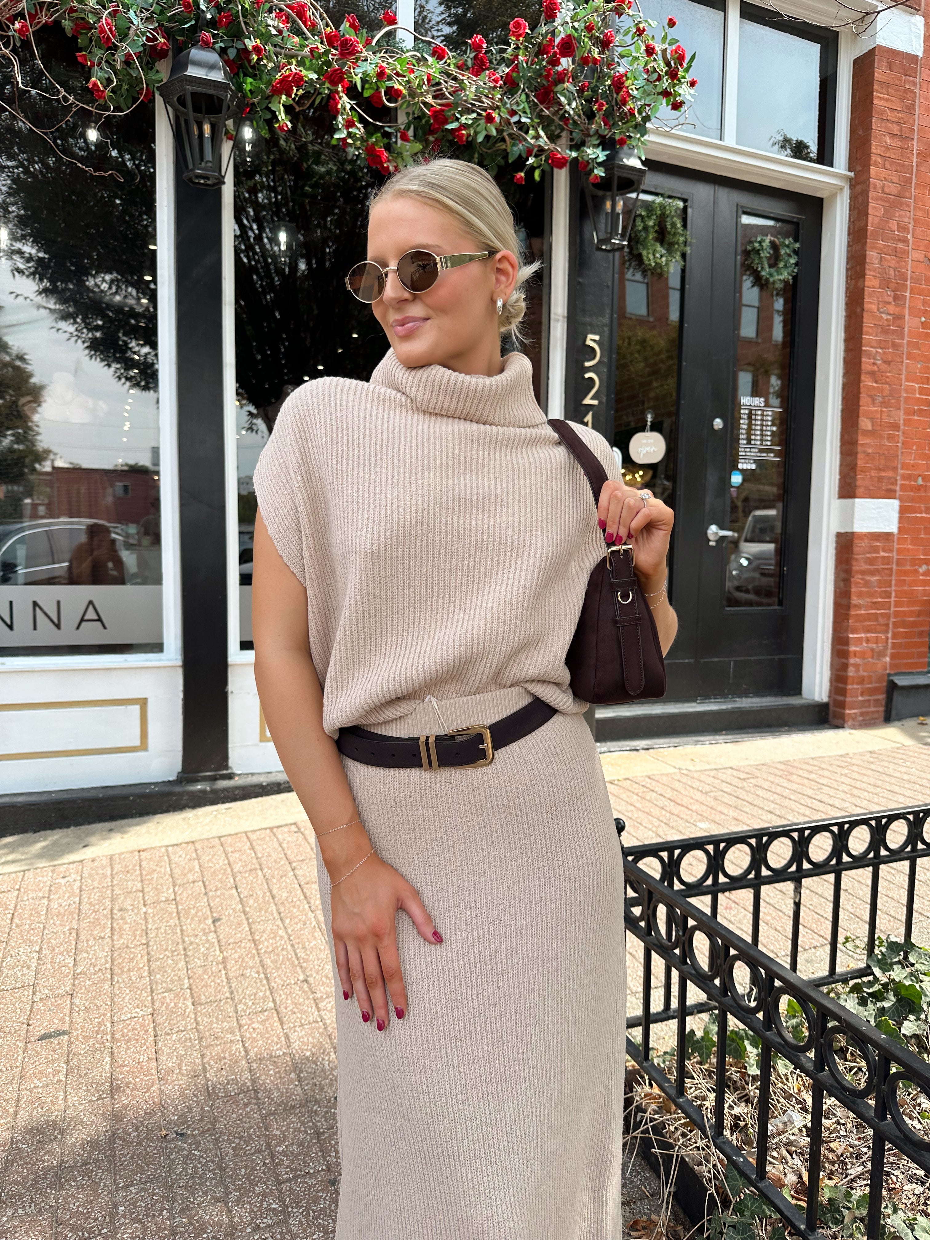 Woman wearing a beige knit two piece sweater set with midi skirt and belt.