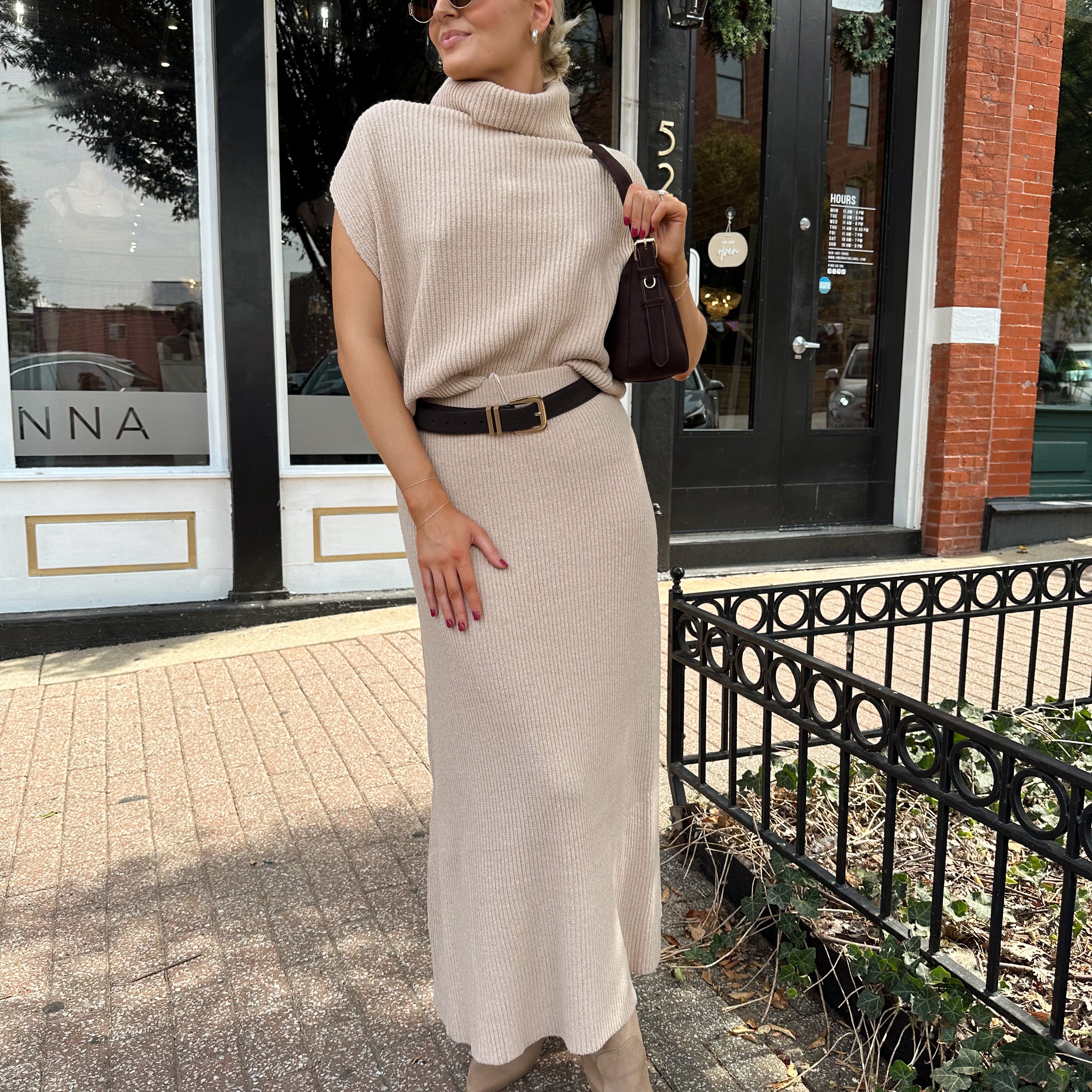 Woman wearing a beige knit two piece sweater set with midi skirt and belt.