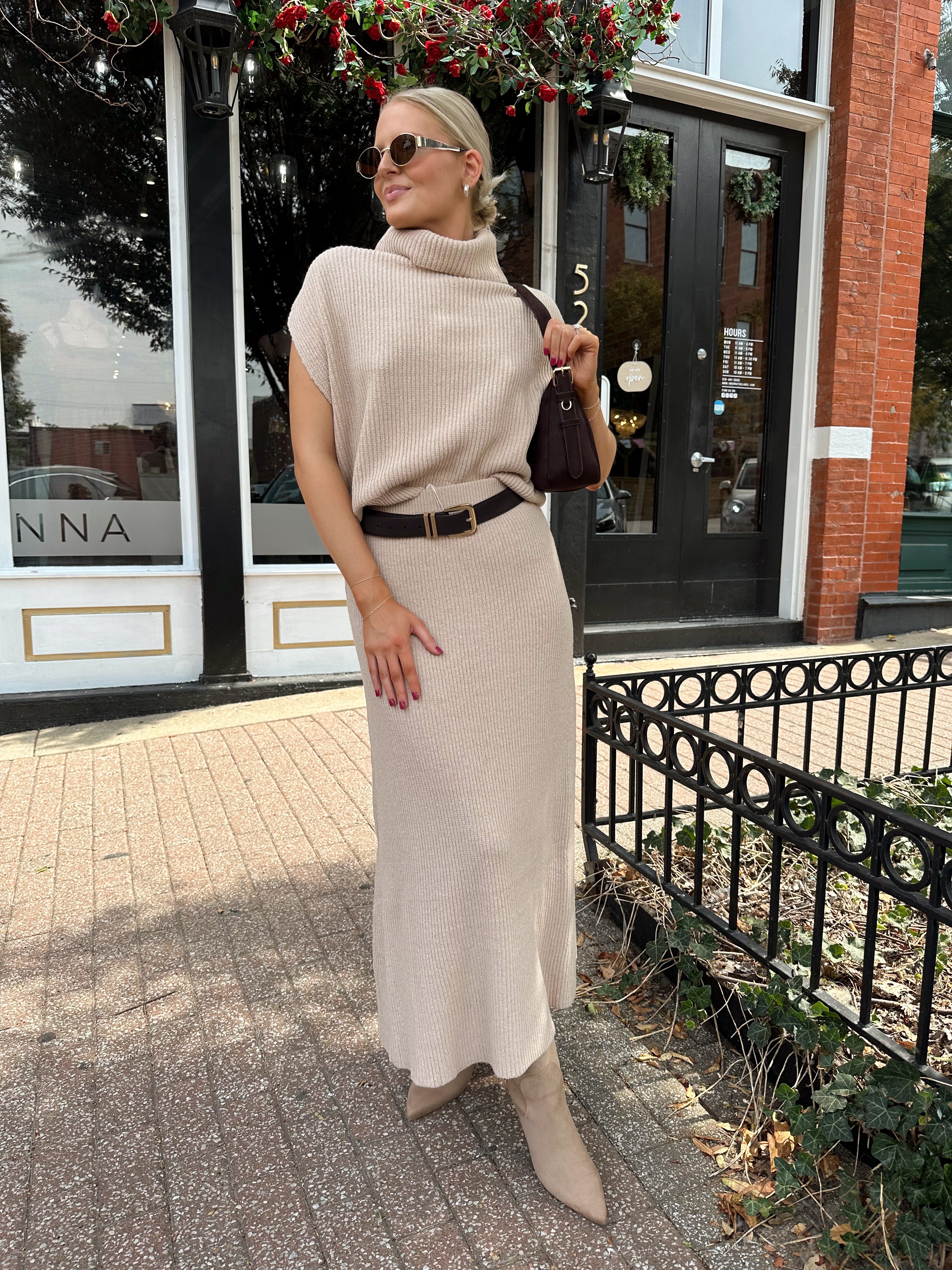 Woman wearing a beige knit two piece sweater set with midi skirt and belt.